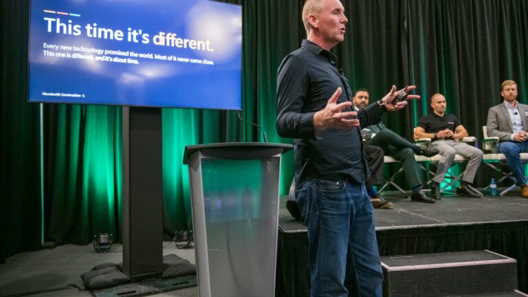 Chris Smith of Woodsmith Construction speaking on The AI Builder panel at the 2026 OHBA Annual Conference at Blue Mountain, beside a screen reading "This time it's different."